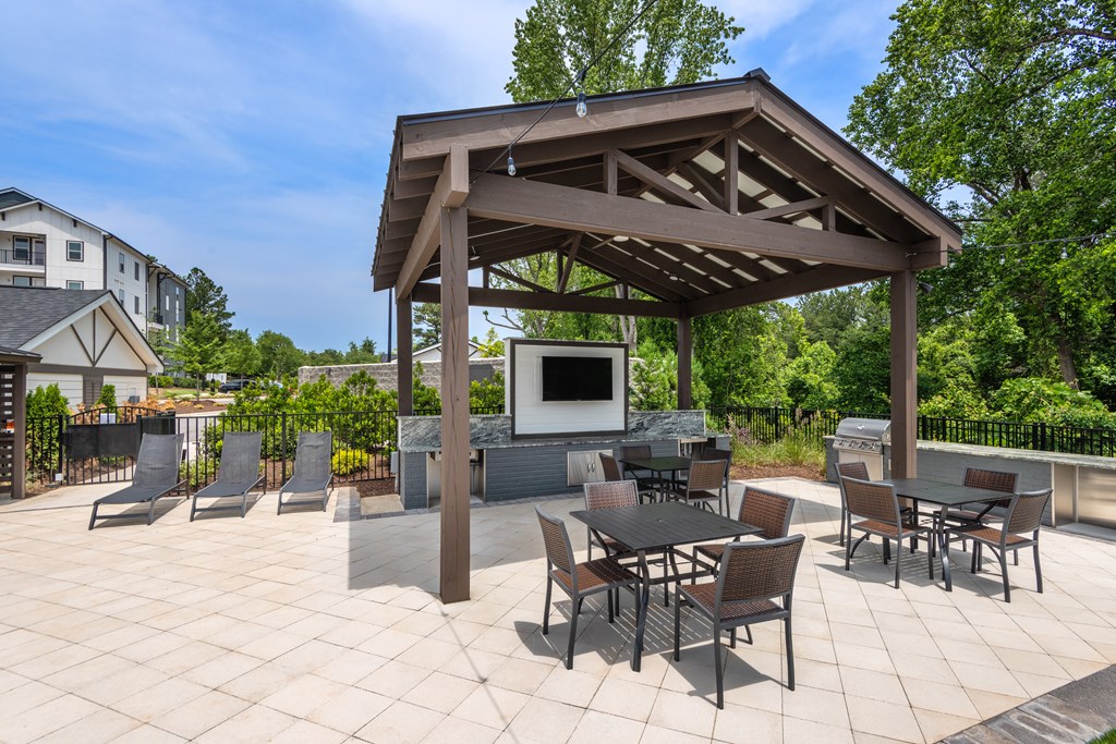 a patio with tables and chairs and a television in a pavilion