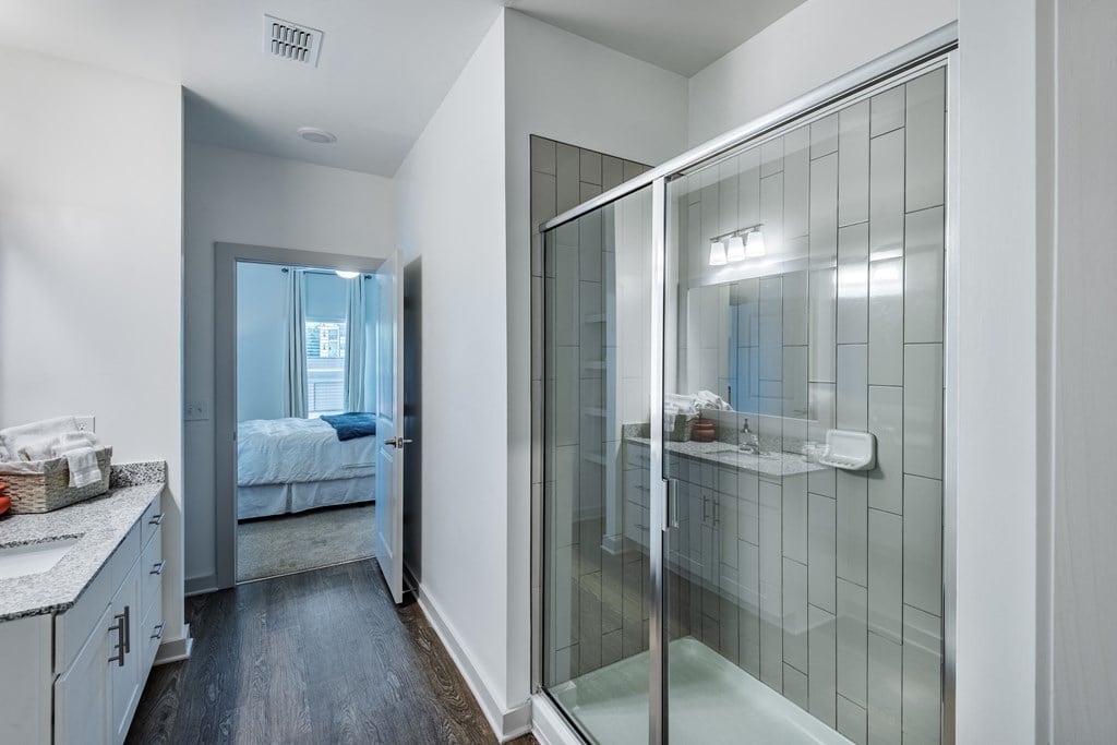 a bathroom with a glass shower and a bedroom with a bed