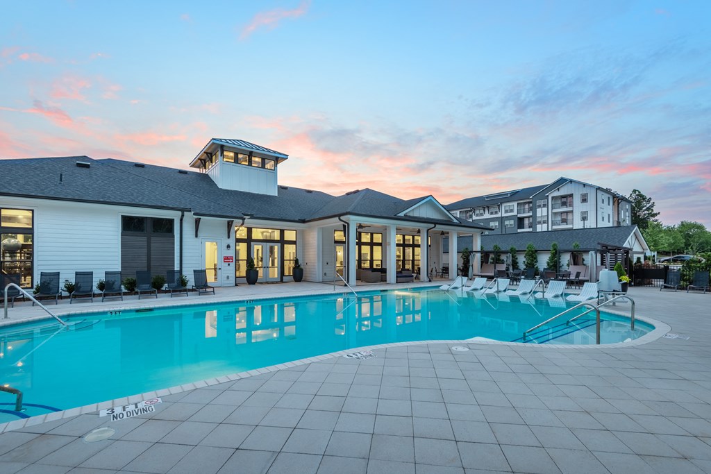 a swimming pool with chairs and a building in the background