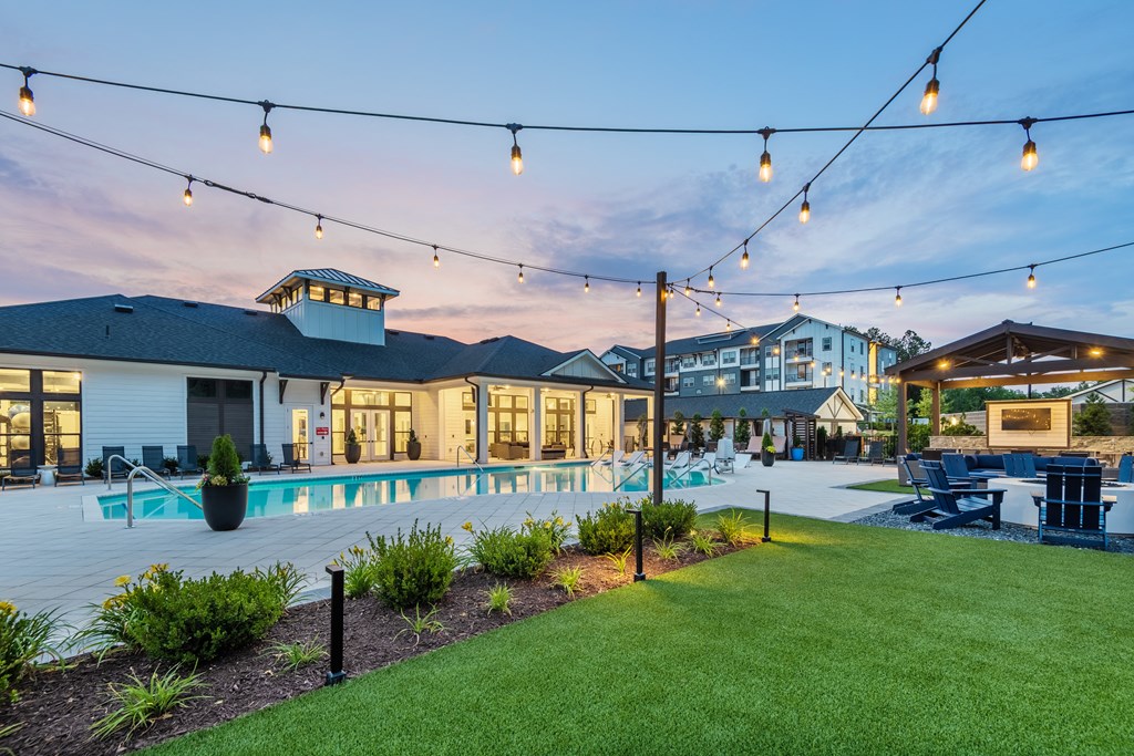 a yard with a swimming pool and a building with patio furniture