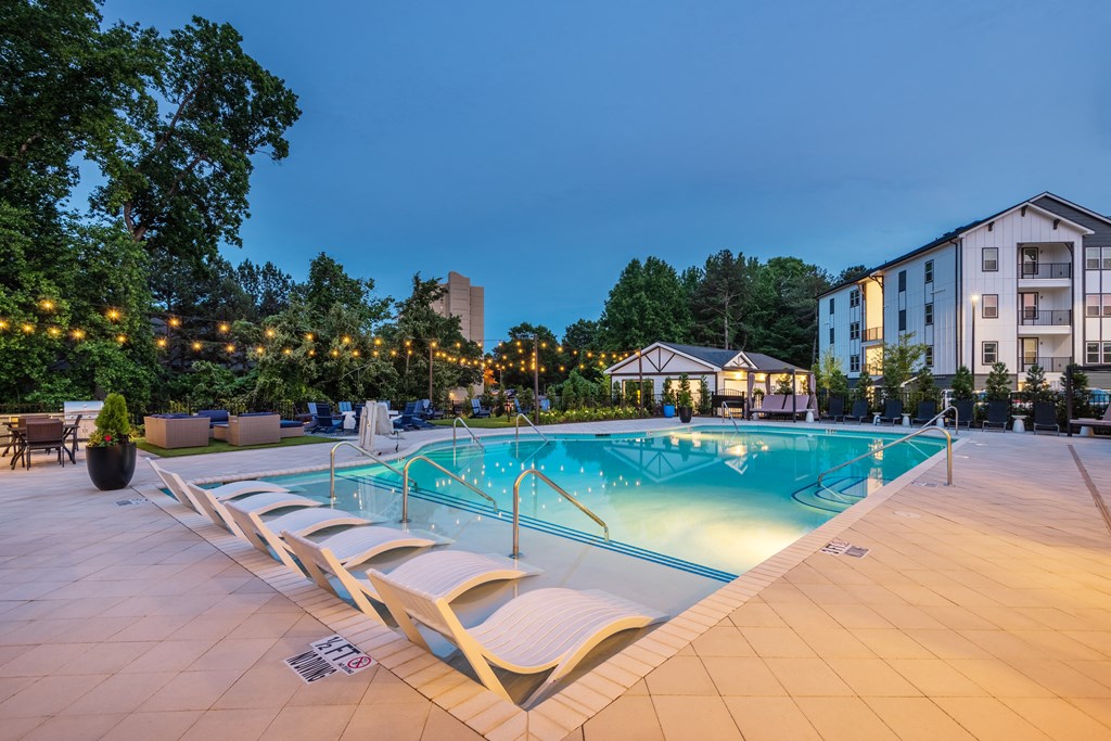 a swimming pool at night next to an apartment building