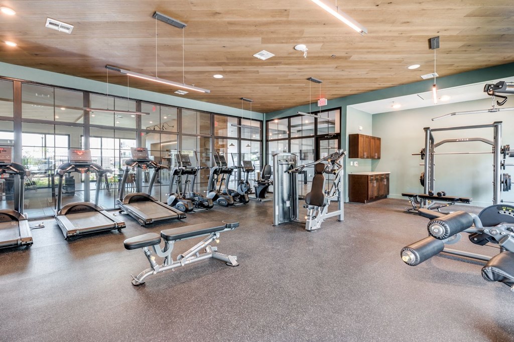 a gym with cardio equipment and glass walls