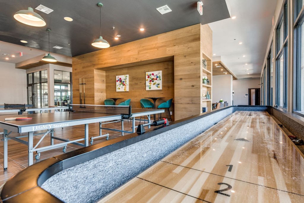 a large gym with a pool and ping pong table in a building with windows