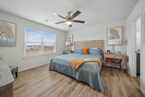 A bedroom with a bed, a ceiling fan, and a window with blinds.