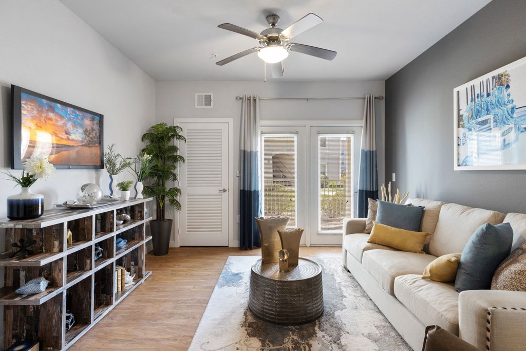 A living room with a white couch, a wooden floor, and a ceiling fan.