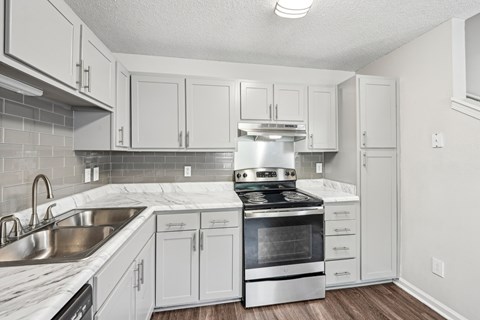 A kitchen with white cabinets and a stainless steel oven.