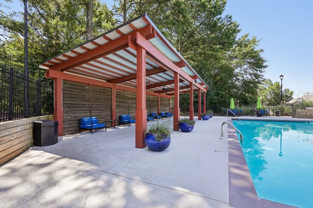 A pool area with a red roofed pavilion and a pool with a ladle in it.