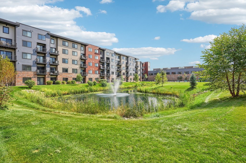 A row of apartment buildings with a fountain in the foreground.