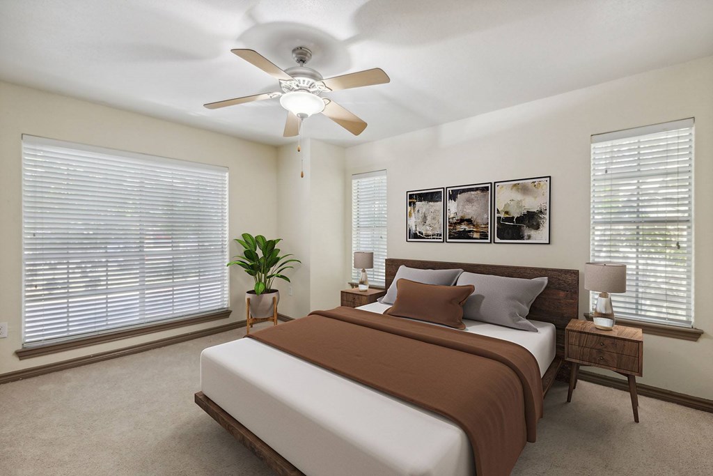 A bedroom with a bed, a ceiling fan, and a potted plant.