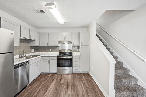 A kitchen with white cabinets and a stainless steel refrigerator.