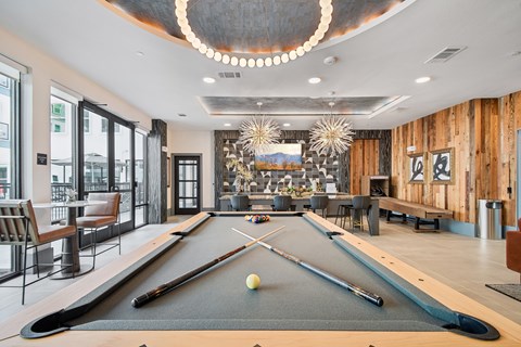 A pool table is in the middle of a room with a bar and a dining area.