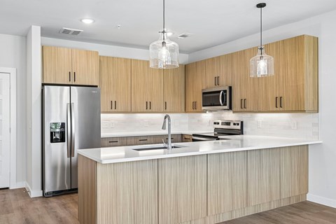 A modern kitchen with wooden cabinets and a stainless steel refrigerator.