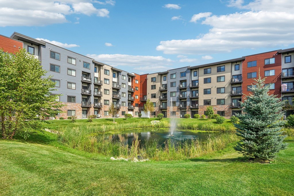 A row of modern apartment buildings with a pond in the foreground.