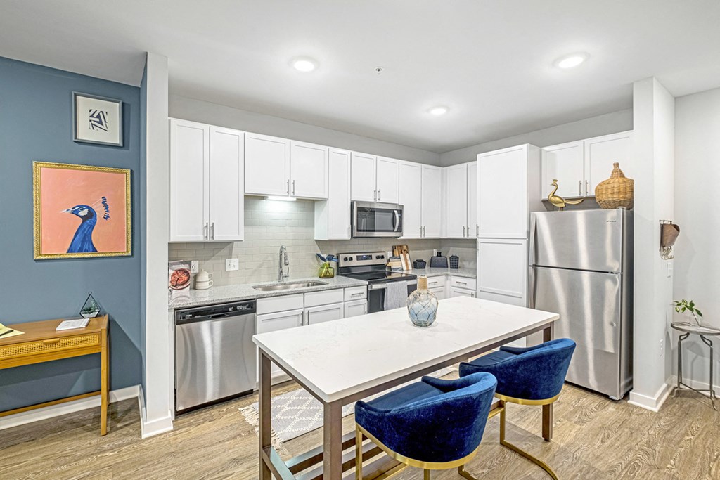 a kitchen with white cabinets and stainless steel appliances and a white table with blue chairs