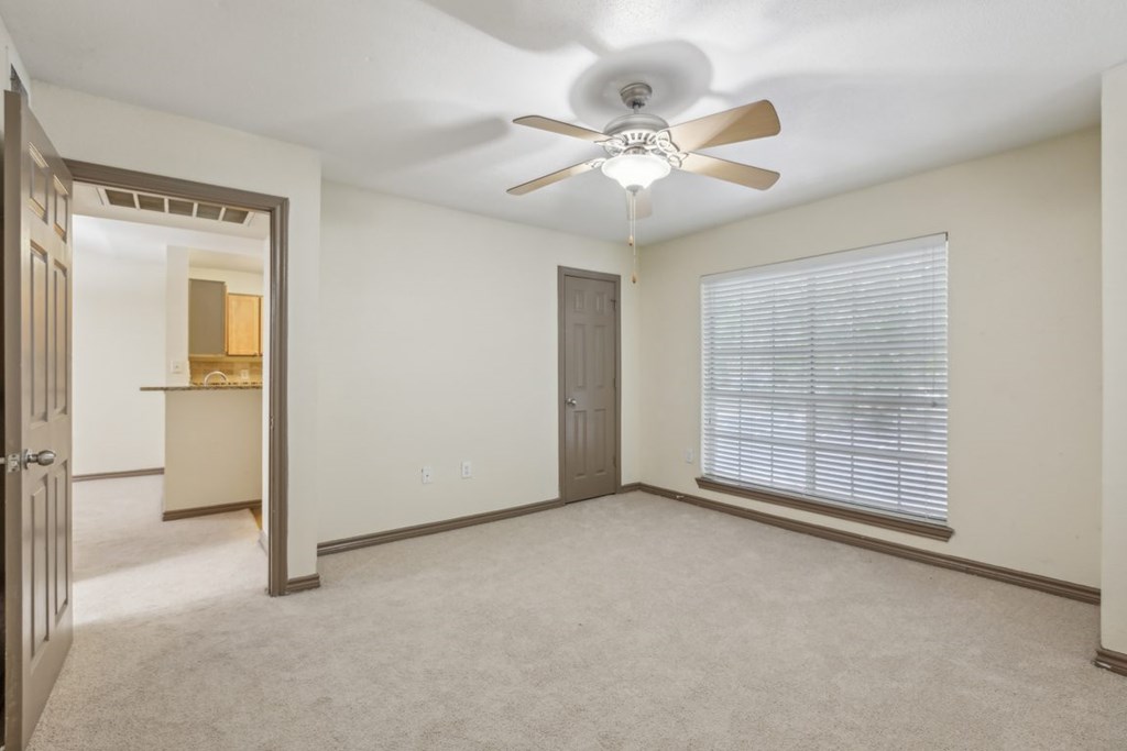 A room with a ceiling fan and a window with blinds.