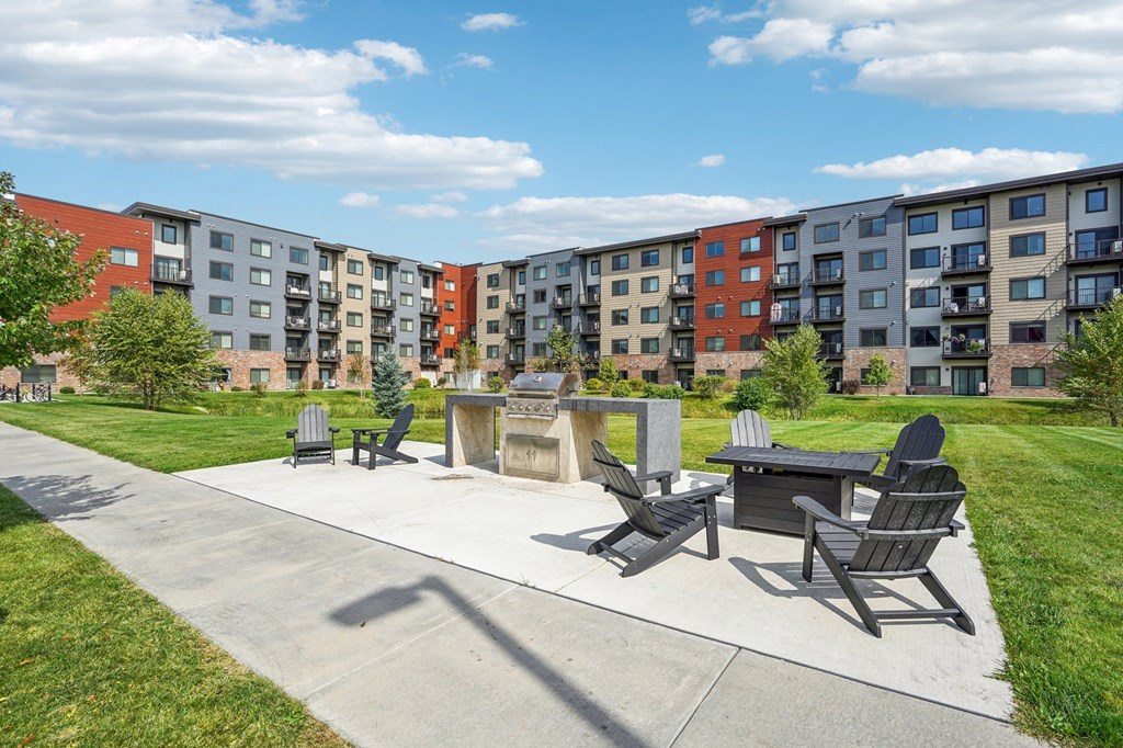 A sunny day at a park with a concrete table and chairs and apartment buildings in the background.