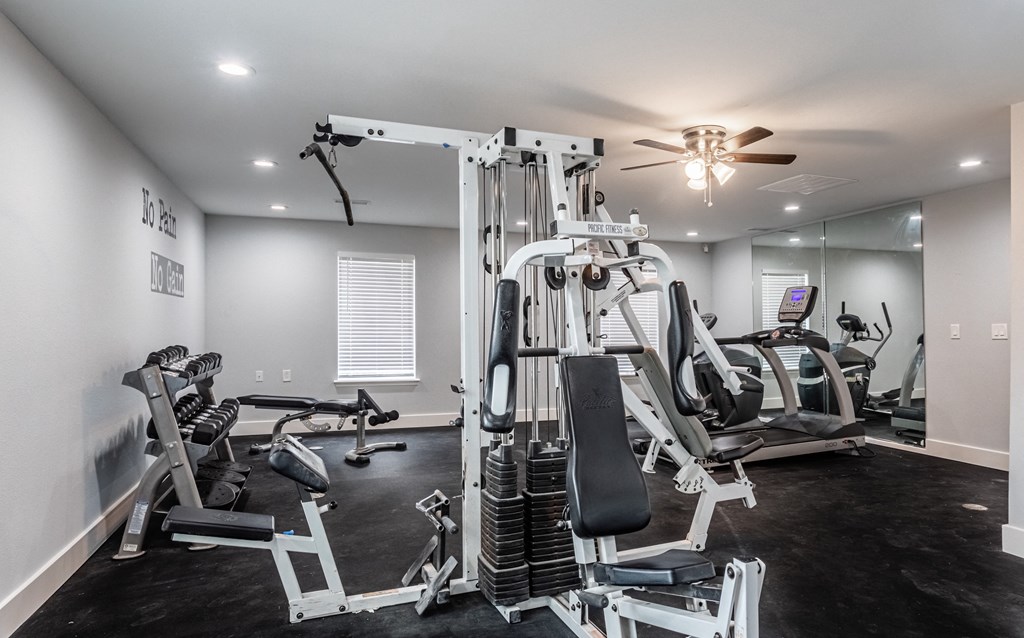a gym with cardio machines and a ceiling fan