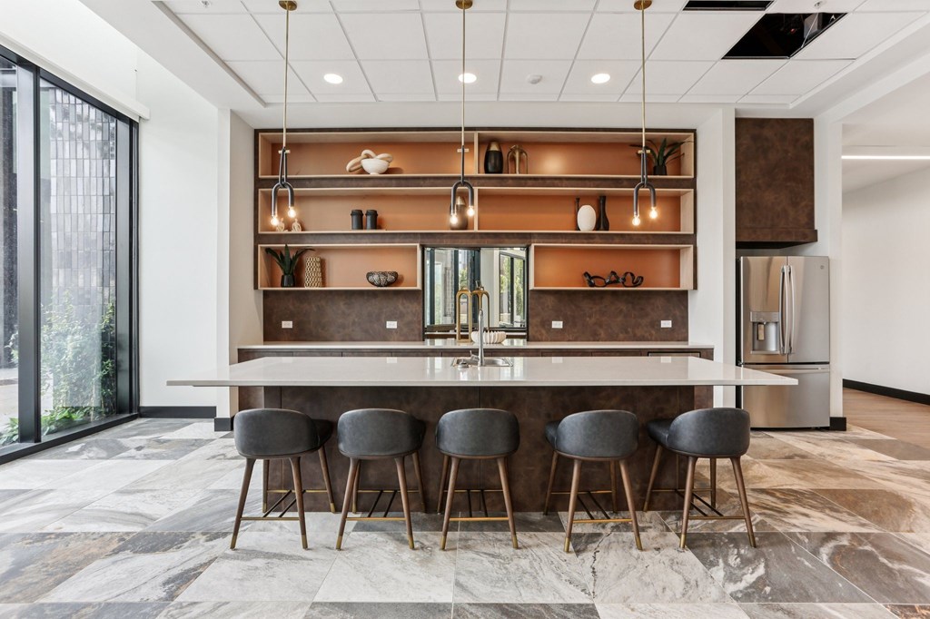 A modern kitchen with a bar area and grey chairs.