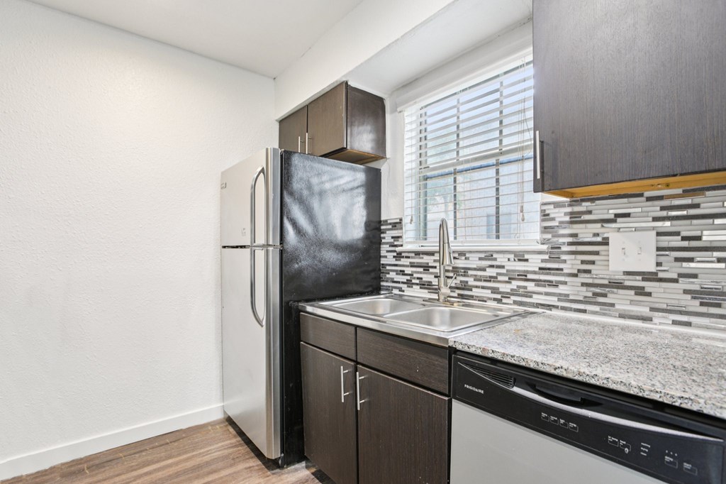 A kitchen with a black fridge and a black dishwasher.