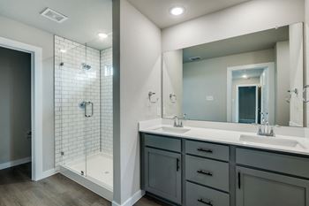 A bathroom with a walk-in shower and double sinks.