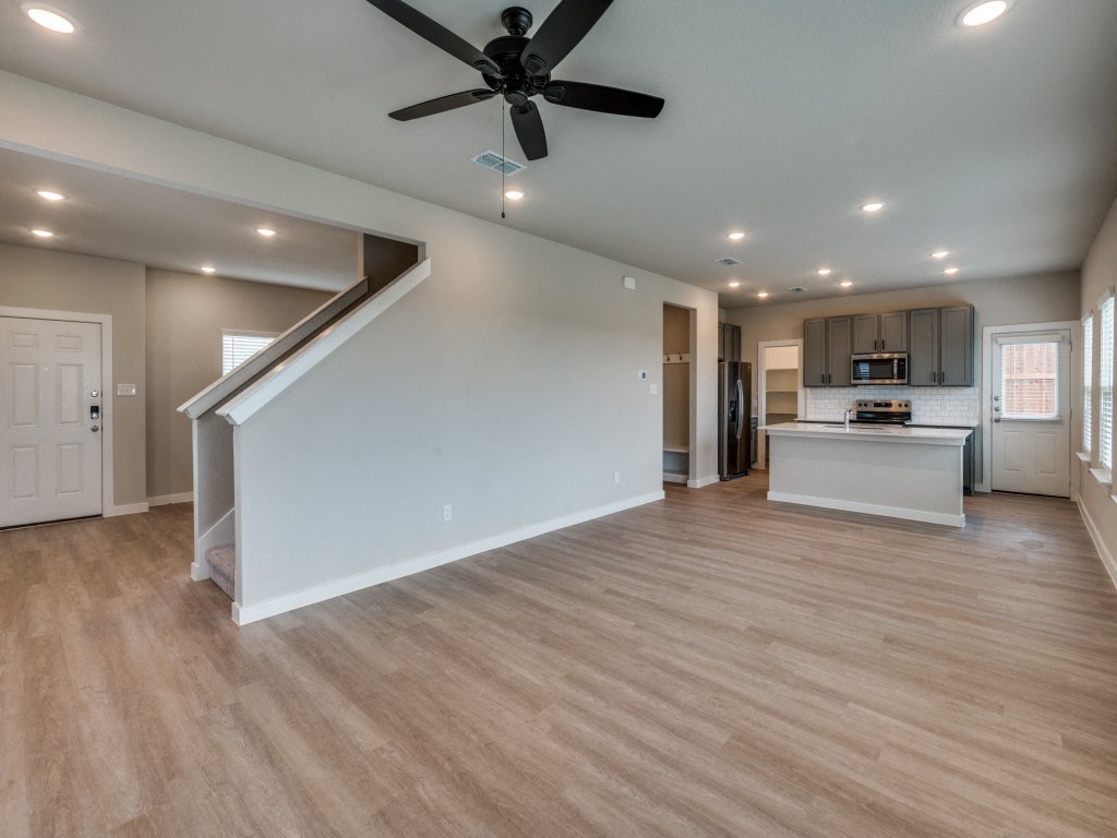 A spacious room with a ceiling fan and lighting fixtures.