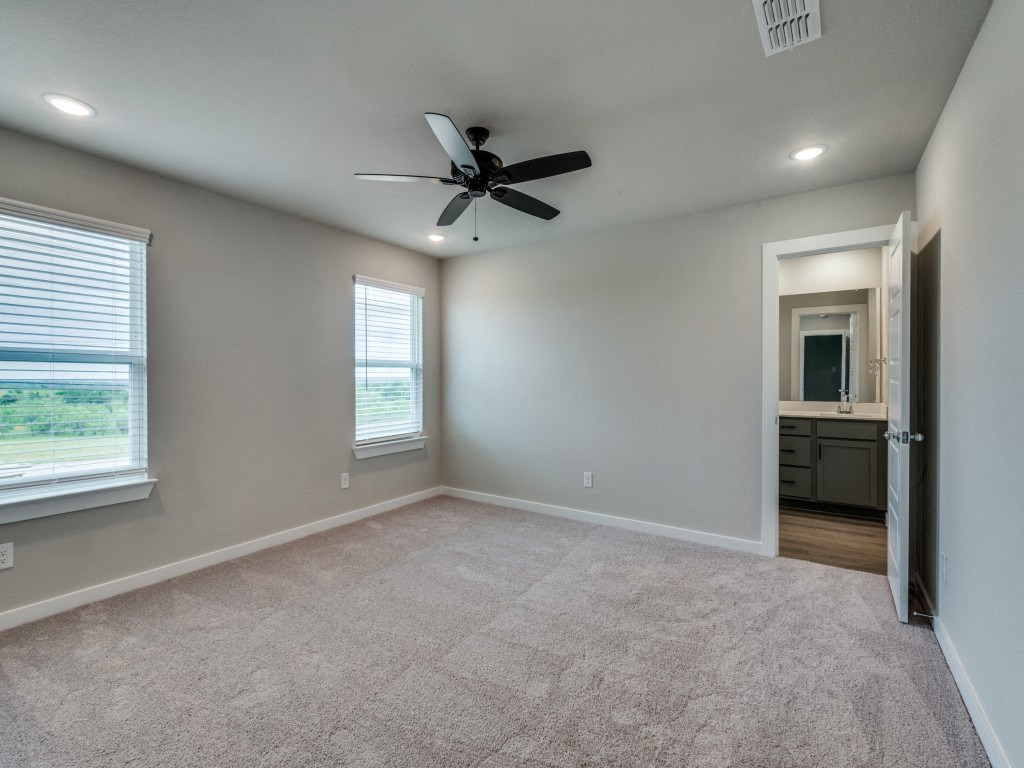 A room with a ceiling fan and carpeted floor.