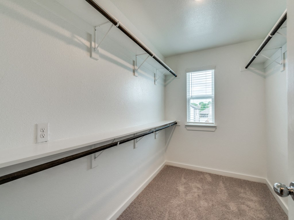 A room with a carpeted floor, a window with blinds, and a white wall with a black trim.