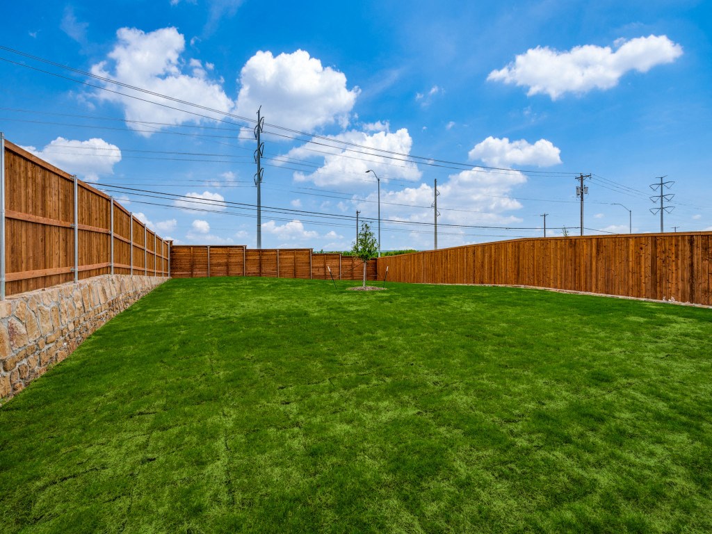 A backyard with a wooden fence and a green lawn.