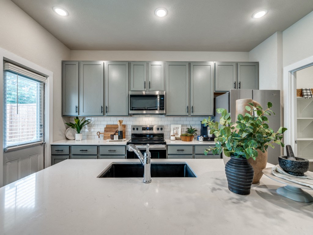 A kitchen with a white countertop and grey cabinets.