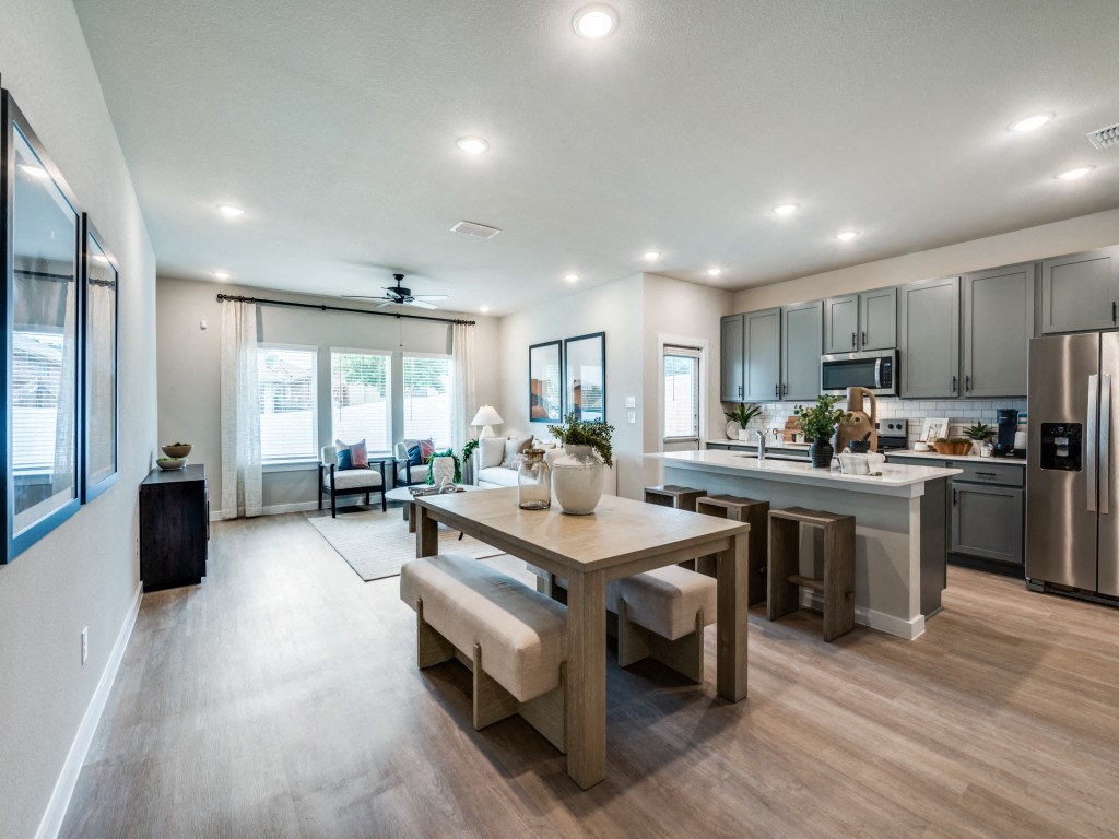 A modern kitchen with a dining table and chairs in the middle of the room.