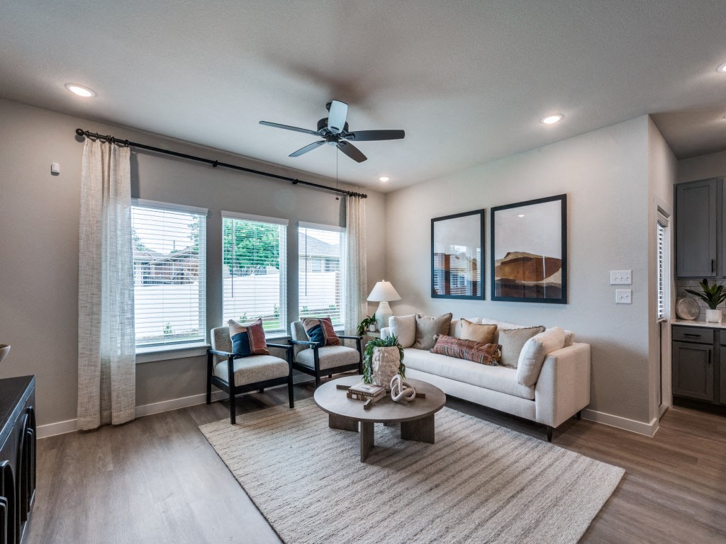 A living room with a white couch, a coffee table, and a ceiling fan.