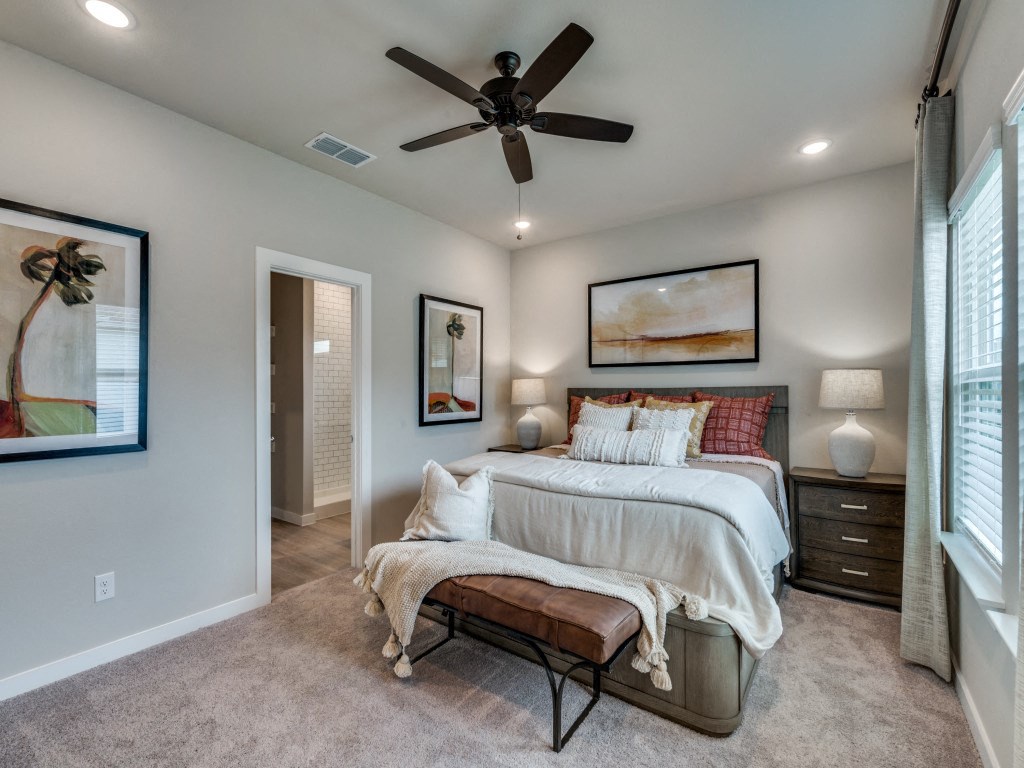 A bedroom with a bed, bench, and artwork on the wall.