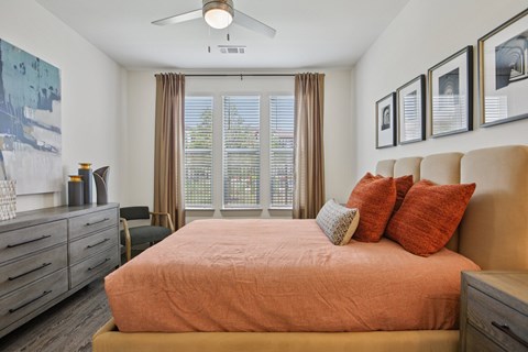 A bedroom with a bed, dresser, and a ceiling fan.