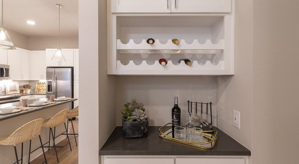 a kitchen with white cabinets and a counter top with a wine glass