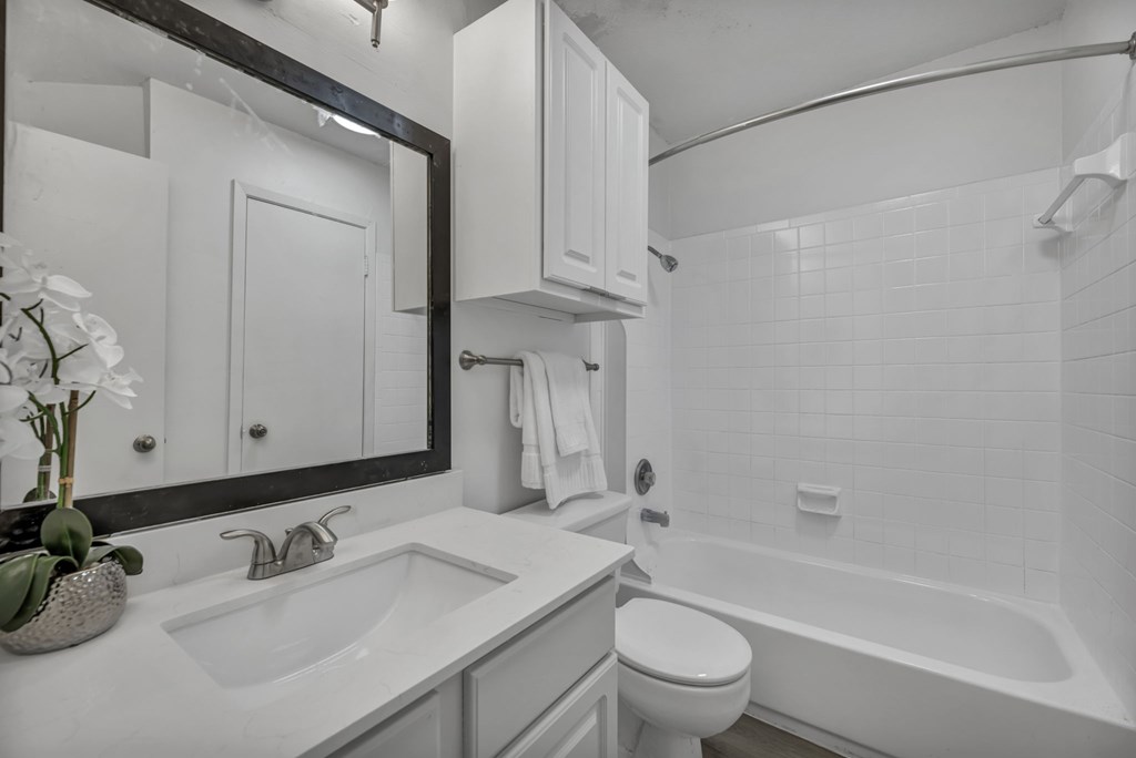 A white bathroom with a sink, toilet and bathtub.