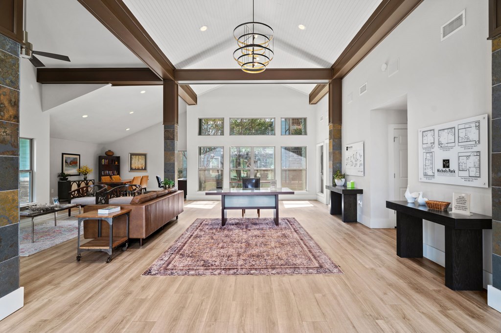 A large, open living room with a rug on the floor and a long table with chairs.