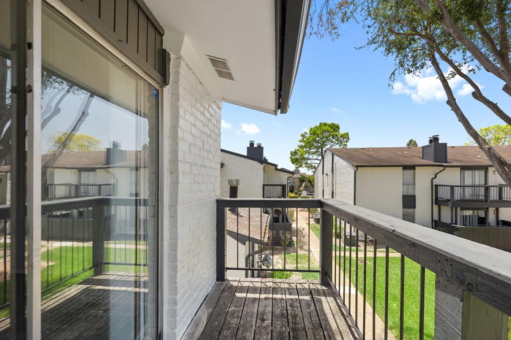 a view from the balcony of a house with a yard and a tree