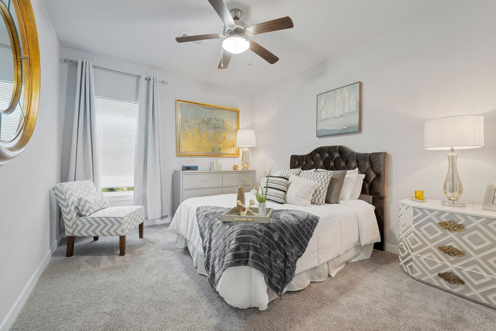 A bedroom with a bed, chair, and a painting on the wall.