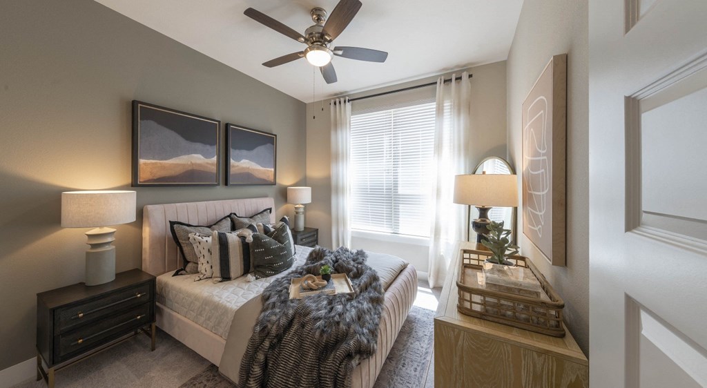 a bedroom with a ceiling fan and a large window