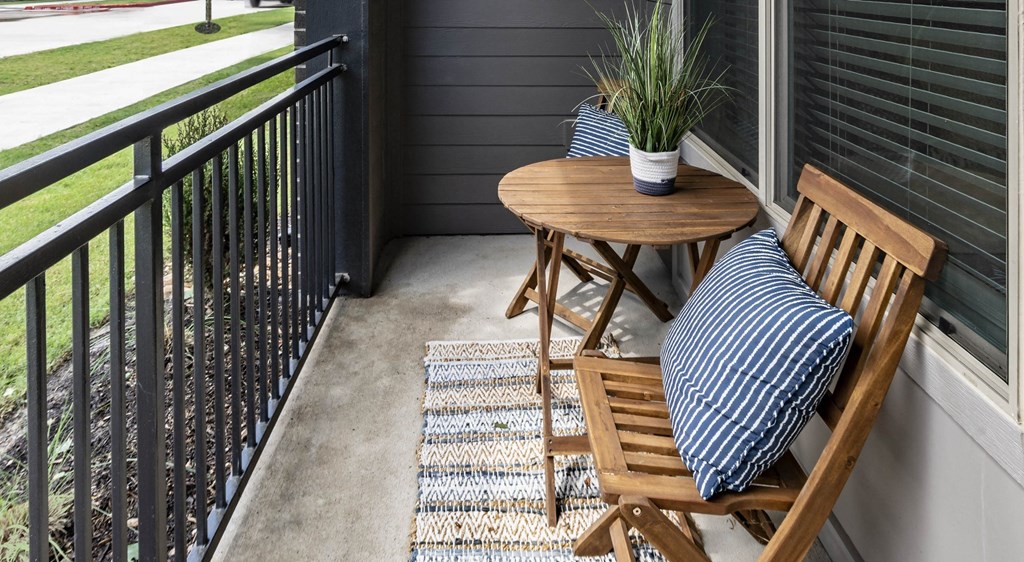 a small patio with a wooden table and chairs on a balcony