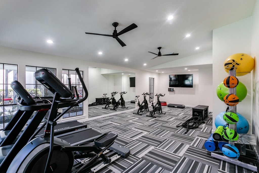 a gym with cardio equipment and weights on a checkered floor