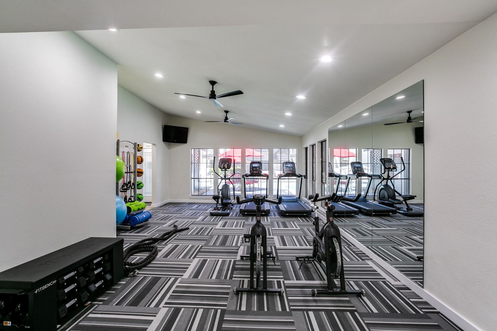 a gym with treadmills and other exercise equipment in a large room with windows