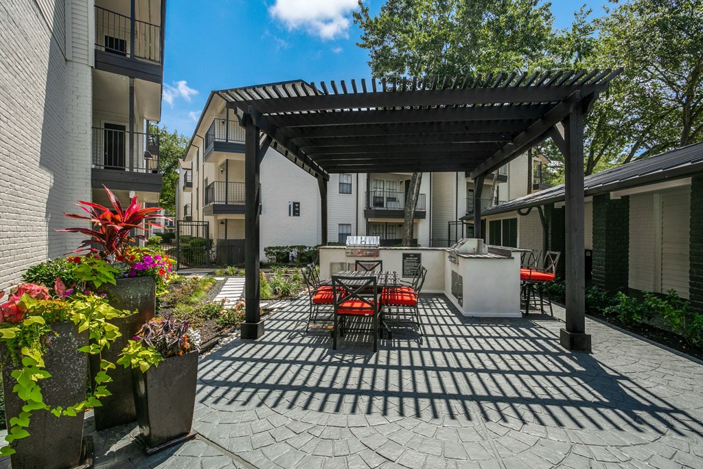 a patio with a table and chairs and a grill