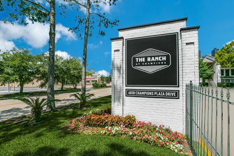 the ranch apartments sign in front of grass and flowers