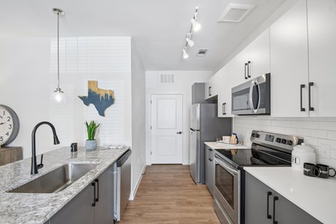 A kitchen with a white counter top and a stainless steel sink.