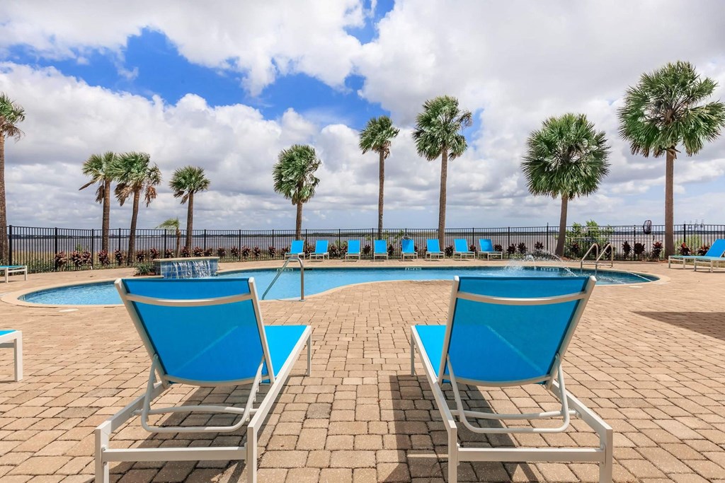 a pool with blue lounge chairs and palm trees