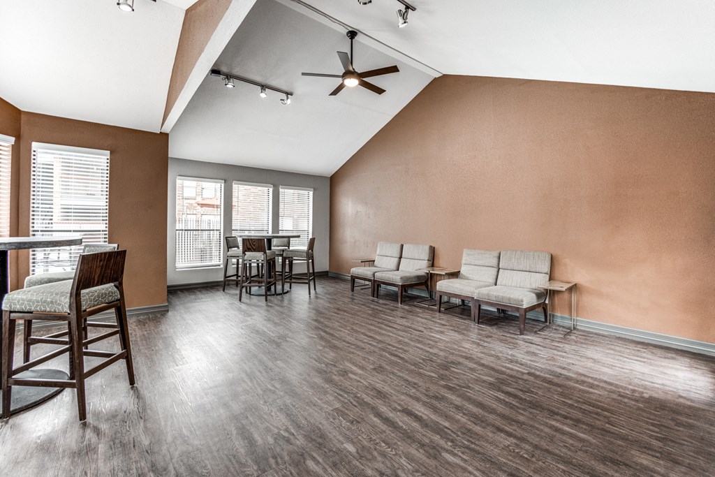 an empty living room with chairs and a dining room table and a ceiling fan