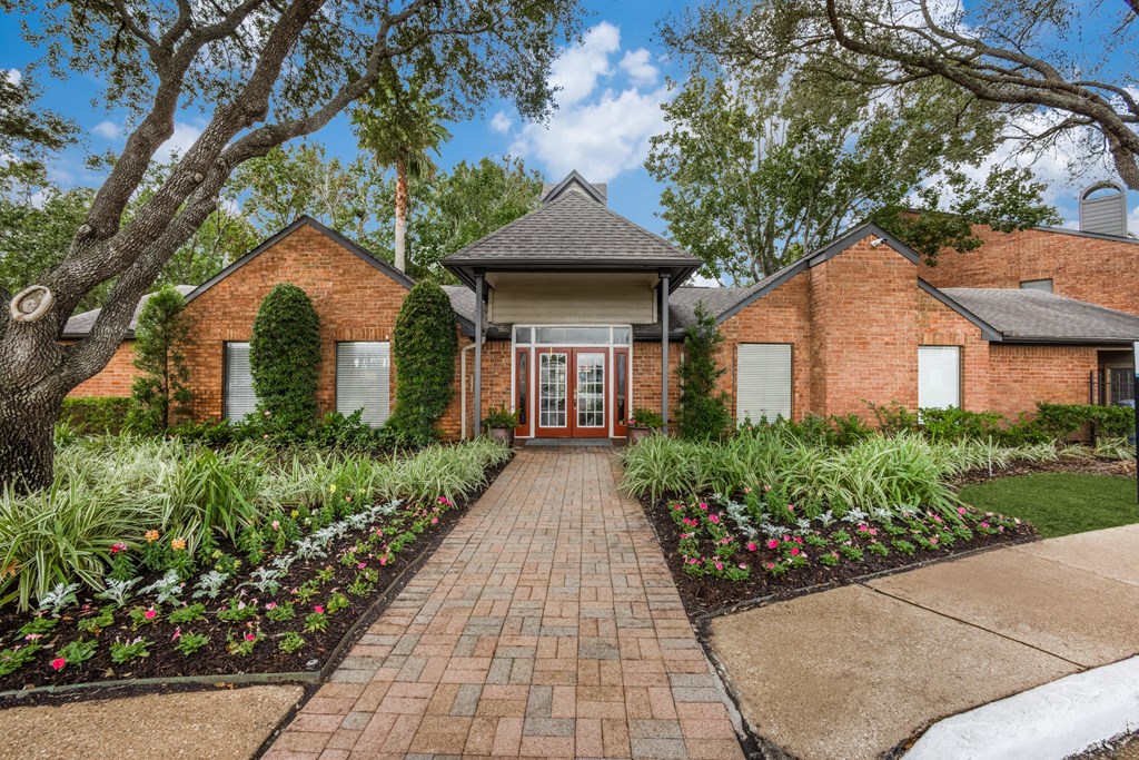 the front of a brick house with a brick pathway and landscaping
