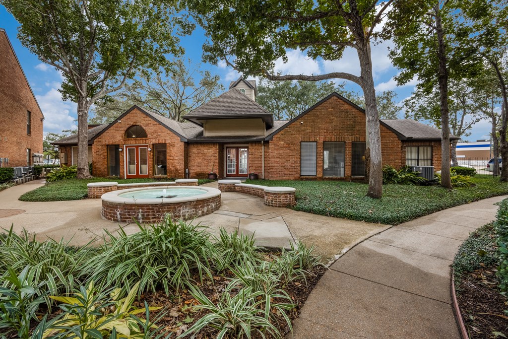 a walkway leading to a brick house with a fountain