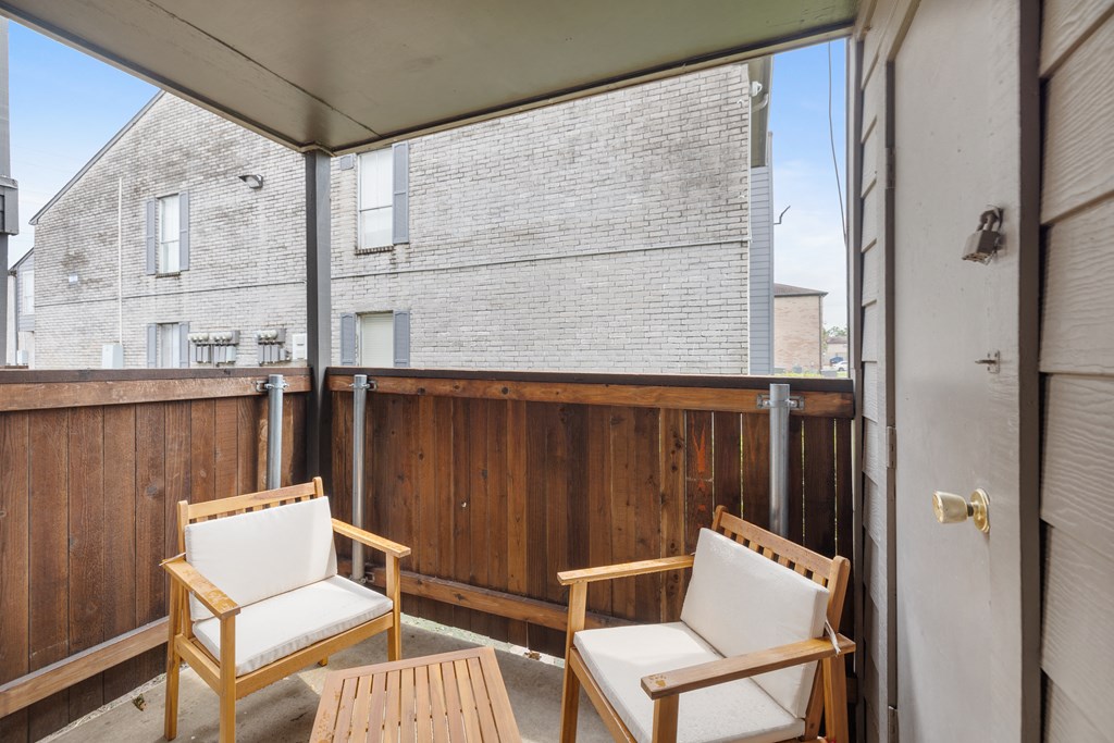 two chairs and a table on a balcony with a sliding glass door